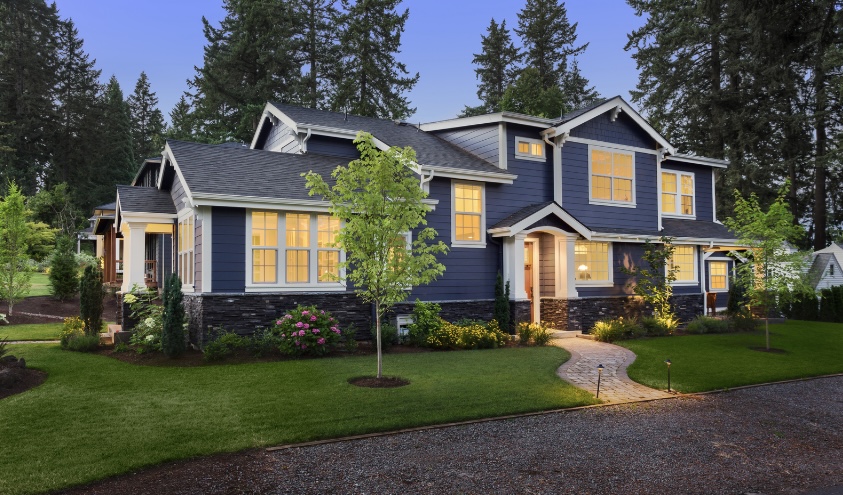 This craftsman-style home features dark blue siding and a textured stone foundation.